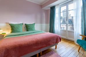 Aux Deux Clochers de Troyes في تروي: غرفة نوم بسرير ونافذة كبيرة