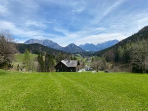 a house in a field with mountains in the background at Alex´s Ferienwohnung in Altaussee