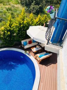 a swimming pool with chairs and a umbrella on a deck at VİA PERLA BUTİK OTEL in Çiftlikköyü