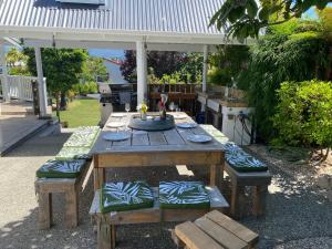a wooden picnic table with benches and a grill at The cottage at the Gables in Motueka