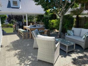 a patio with wicker chairs and a table and a grill at The cottage at the Gables in Motueka