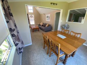 a dining room and living room with a wooden table and chairs at The cottage at the Gables in Motueka