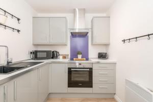 eine weiße Küche mit weißen Schränken und einem Waschbecken in der Unterkunft Stylish & Modern 2 Bed 2 Bath With Free Parking in Leeds