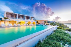 a resort swimming pool with a view of the ocean at Rock House in Providenciales