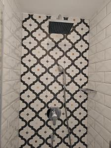 a shower in a bathroom with a black and white tile wall at Little house in Baška in Baška