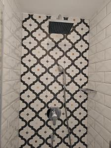 y baño con ducha y pared de azulejos blancos y negros. en Little house in Baška, en Baška