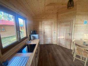 a kitchen in a log cabin with a sink and a table at Domek z widokiem jeziora in Borsk +16 photos