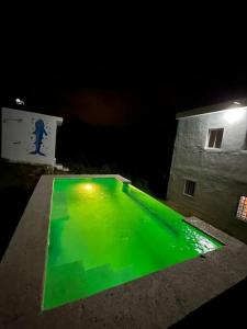- une piscine verte en face d'un bâtiment la nuit dans l'établissement Casita Yanella, à Cabrera