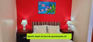 a bedroom with a red wall with a bed and two lamps at Príncipe de Mónaco Boutique House in Angra do Heroísmo