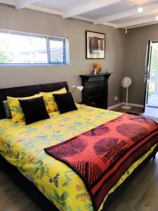 1 dormitorio con 1 cama grande y edredón colorido en Blissful Country Garden Self-Catering Cottage, en Grabouw
