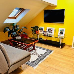 un salon avec une télévision sur un mur jaune dans l'établissement Elegancia del JJM, à Annemasse