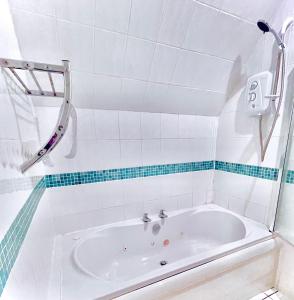 a bath tub in a white tiled bathroom at The Crows Nest in Eyemouth