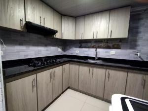 a kitchen with wooden cabinets and a sink at THE PIRAEUS in Soacha