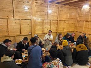 un grupo de personas sentadas en mesas comiendo comida en West coast surf house, en Imsouane