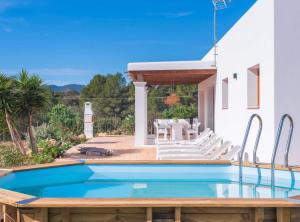 a pool with white chairs and a house at Villa Sa Planeta in Sant Josep de Sa Talaia