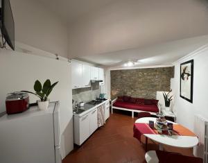 Domus Isidis room camera singola con cucina في بينيفنتو: مطبخ وغرفة معيشة مع أريكة حمراء في غرفة