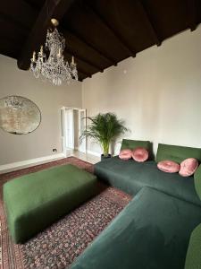 a living room with a green couch and a chandelier at Room Manzoni 37 in Cremona +20 photos