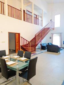 a dining room with a table and chairs and a staircase at La Maison Blanche in Bafoussam