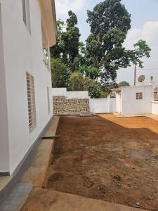 an empty courtyard of a white building with trees in the background at La Maison Blanche in Bafoussam