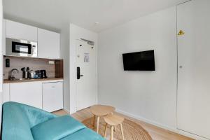 ein Wohnzimmer mit einem blauen Sofa und einer Küche in der Unterkunft Small and modern apartment 11rd Paris in Paris