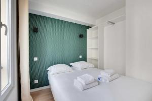 a bedroom with two beds and a green wall at Small and modern apartment 11rd Paris in Paris
