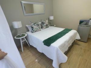 a bedroom with a white bed with pillows and a mirror at Zhantique Guest House Unit 5 in Boksburg