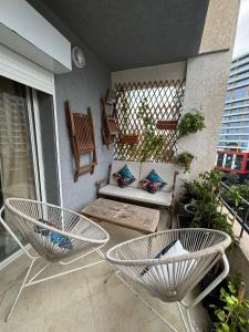 een patio met 2 stoelen en een bank op een balkon bij Studio Plage Malabata tanger in Tanger