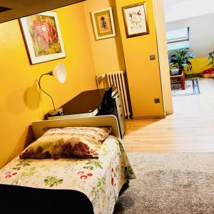 1 dormitorio con cama y pared amarilla en Elegancia del JJM, en Annemasse