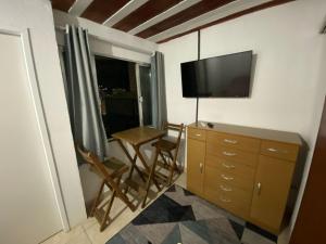 a room with a tv and a dresser with a table and a chair at Suite 3, Casa Amarela, Terceiro Andar in Nova Iguaçu
