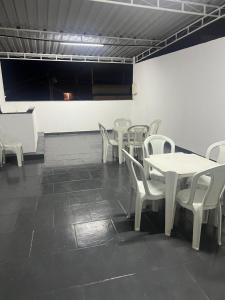 una sala da pranzo con tavoli bianchi e sedie bianche di Suite 3, Casa Amarela, Terceiro Andar a Nova Iguaçu