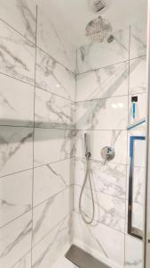 La salle de bains est pourvue d'une douche et de murs en marbre blanc. dans l'établissement Votre Escale - Magellan Cinéma, à Niort