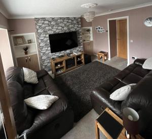 ein Wohnzimmer mit einem Ledersofa und einem Flachbild-TV in der Unterkunft 5 Riverside Place Thurso. 2 bed, 2 bathrooms. in Thurso