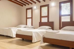 three beds in a room with windows and white walls at CABAÑA TAYRONACA in Calabazo