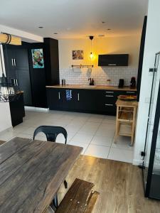 a large kitchen with a wooden table and a counter at Maison familiale 4 chambres avec jardin et piscine in Saint-Aignan-Grand-Lieu