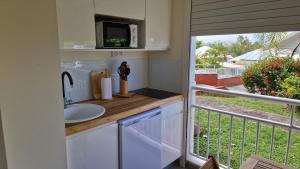 a kitchen with a sink and a microwave on a balcony at Studio Tartane in La Trinité