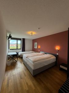 een slaapkamer met 2 bedden en een raam bij Jura Sport & Spa Resort in Saignelégier