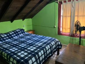 Un dormitorio con una cama azul y blanca a cuadros y una ventana en Lobos, en Aguas Dulces