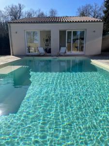 uma piscina com água azul em frente a uma casa em Maison de caractère au cœur de la Haute-Saintonge. em Champagnolles
