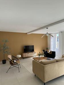 ein Wohnzimmer mit einem Sofa und einem TV in der Unterkunft Maison de caractère au cœur de la Haute-Saintonge. in Champagnolles