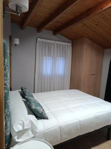 sypialnia z dużym białym łóżkiem i drewnianym sufitem w obiekcie Casa fredi w mieście Cangas de Onís