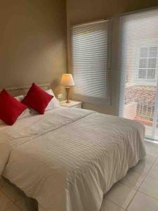 Un dormitorio con una cama blanca con almohadas rojas y una ventana en LaGita Carita Villa, en Carita