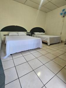 a bedroom with two beds and a tiled floor at Casa 25 hostal in Santa Ana