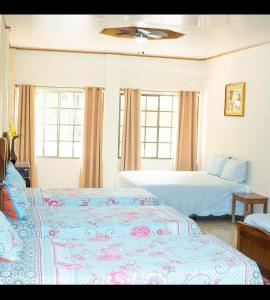 a bedroom with two beds and two windows at Apart Hotel Acuarious de Luis in Estelí