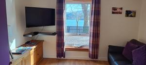 a living room with a tv and a window at Number 4, Loch Shiel View in Glenfinnan
