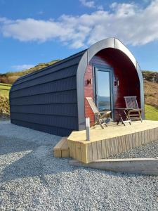 a small red and black building with two chairs in it at Loch Caroy Pods in Ose