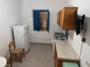 una cucina con frigorifero bianco e finestra blu di Villaggio Camping La Scogliera a Ricadi