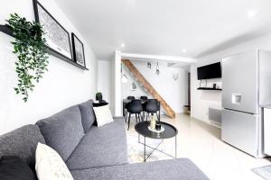 a living room with a gray couch and a table at Maison de ville triplex proche CDG in Sevran