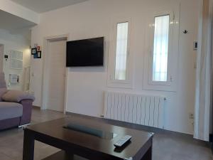 a living room with a couch and a tv on a wall at Suite Poblamar in Pobla de Montornés