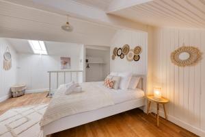 a white bedroom with a large bed and a table at Maison de ville triplex proche CDG in Sevran