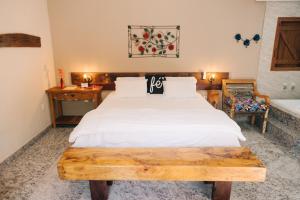 a bedroom with a white bed with a wooden table at Adega Cipó Pousada Serra do Cipó in Serra do Cipo